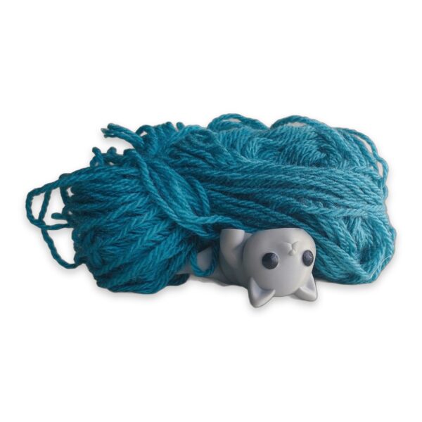 articulated-baby-cat-fidget-toy-poseable-desk-buddy-1 A white articulated cat figure lies curled in front of a skein of teal yarn.