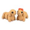 Two tan dachshund figures sitting side by side, one wearing a red bow on its head.