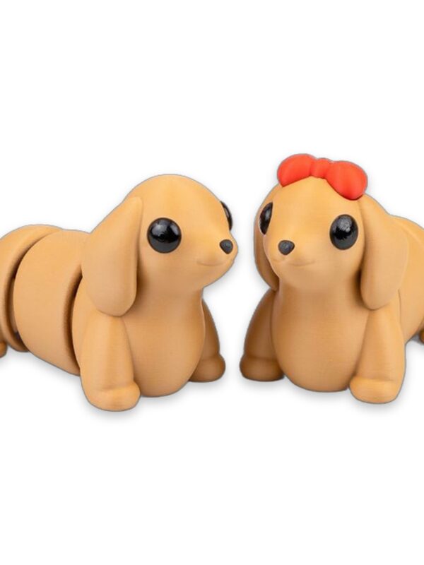 articulated-baby-dachshund-fidget-toy-poseable-desk-buddy-1 Two tan dachshund figures sitting side by side, one wearing a red bow on its head.