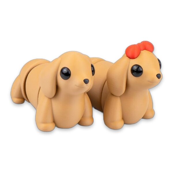 Close-up of two tan dachshund figures, one with a red bow, showing their articulated segmented bodies.