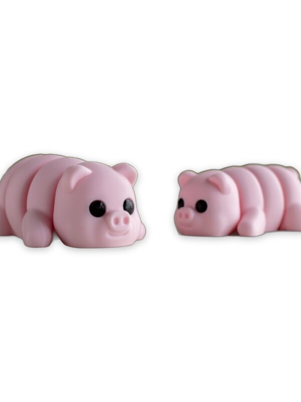 articulated-baby-pig-fidget-toy-poseable-desk-buddy-1 Two pink articulated baby pig figures lying on a table with greenery blurred in the background.
