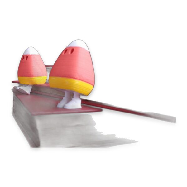 A rear view of two candy corn figures with white shoes standing on top of a book.