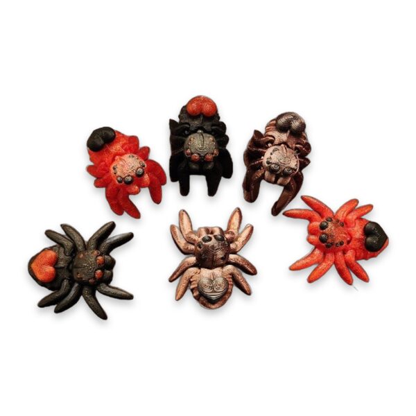 Six articulated heart spiders in red, black, and copper tones arranged on a marble surface.
