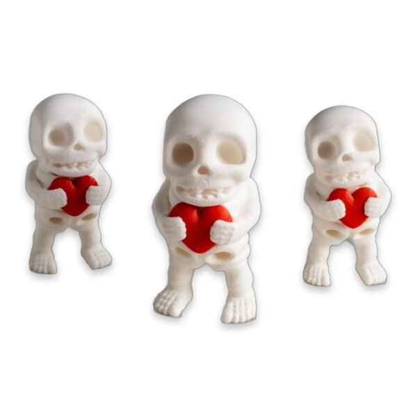 articulated-skeleton-fidget-toy-poseable-desk-buddy-heart-1 A white 3D-printed articulated skeleton figure holding a red heart in both hands, shown in three sizes side by side.