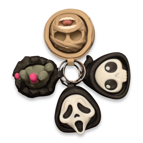 halloween-clickers-fidget-toy-clickable-4 Four Halloween fidget clicker keychains arranged together: a mummy face, a clawed hand, a hooded skull, and a screaming ghost face.