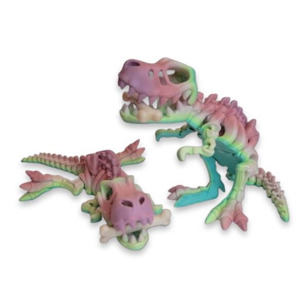 Two pastel rainbow T-Rex skeleton toys lying on their sides, each gripping a bone.